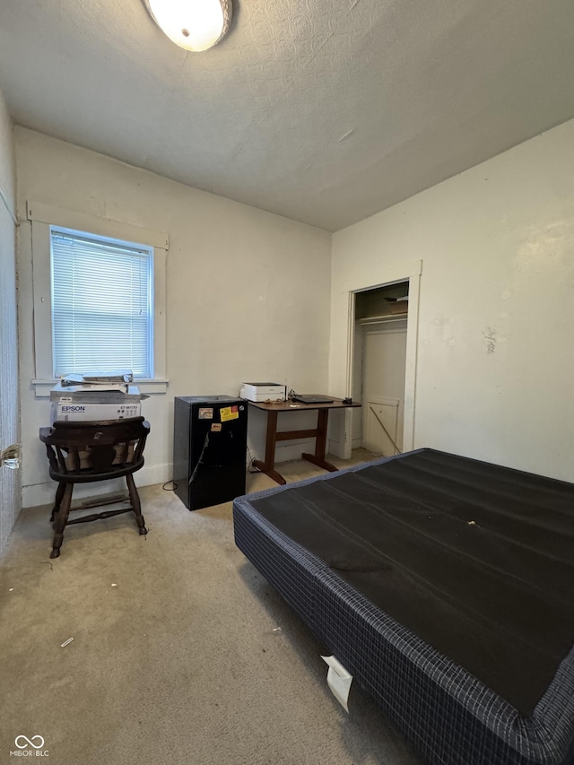 bedroom featuring a textured ceiling and light colored carpet