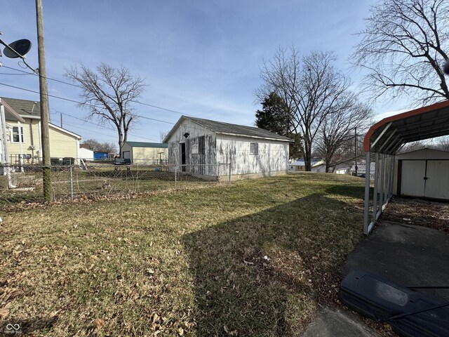 view of yard with a carport, fence, an outdoor structure, and a storage unit