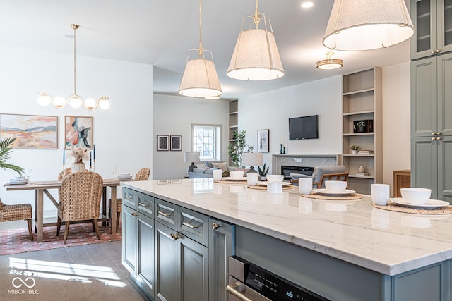 kitchen with decorative light fixtures, open floor plan, gray cabinets, light stone countertops, and glass insert cabinets