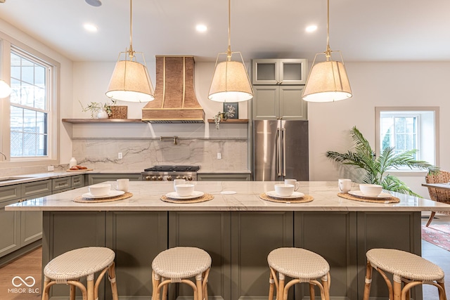 kitchen with gray cabinetry, premium range hood, stove, a sink, and freestanding refrigerator