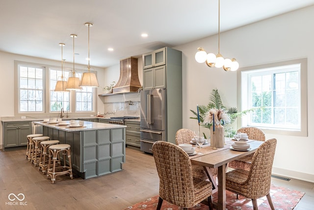 kitchen with custom exhaust hood, stainless steel appliances, light countertops, gray cabinetry, and light wood-type flooring