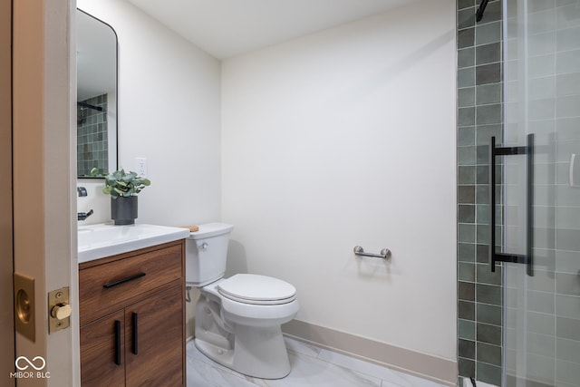 bathroom with a tile shower, vanity, toilet, and baseboards