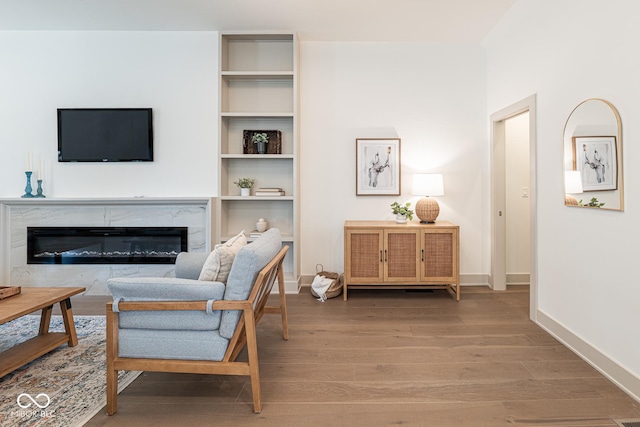 living room featuring a premium fireplace, baseboards, and wood finished floors