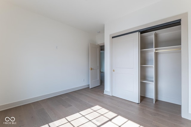 unfurnished bedroom with a closet, wood finished floors, and baseboards