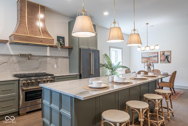 kitchen with light wood finished floors, premium appliances, gray cabinets, and custom range hood