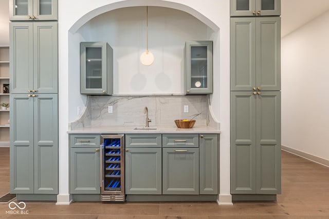 bar with beverage cooler, wood finished floors, a sink, backsplash, and indoor wet bar