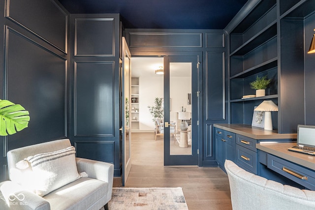 interior space featuring built in shelves, a decorative wall, and wood finished floors