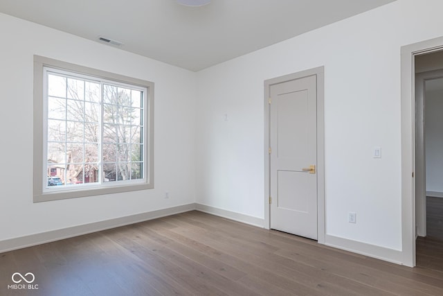 empty room featuring baseboards, visible vents, and wood finished floors