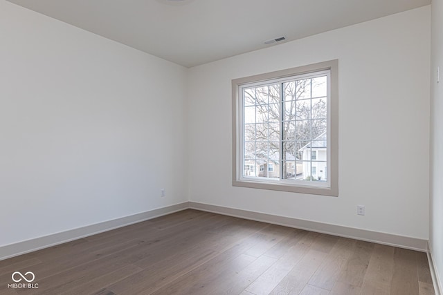 unfurnished room with visible vents, baseboards, and wood finished floors