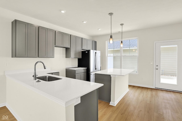 kitchen with light wood finished floors, a sink, freestanding refrigerator, and gray cabinetry