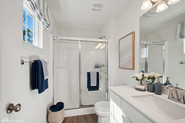 full bathroom with toilet, wood finished floors, visible vents, vanity, and a stall shower