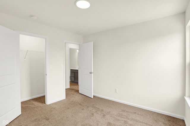 unfurnished bedroom with a closet, light colored carpet, and baseboards