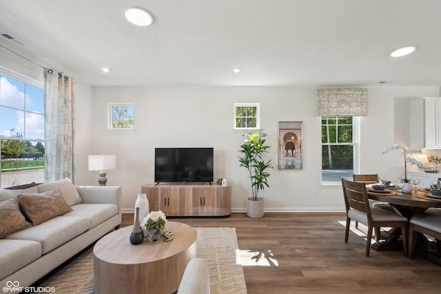 living area with a wealth of natural light, visible vents, recessed lighting, and wood finished floors