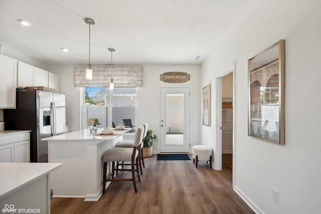 kitchen featuring light countertops, a breakfast bar, white cabinets, and stainless steel refrigerator with ice dispenser