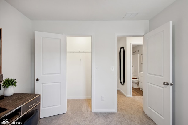 bedroom featuring light carpet, visible vents, baseboards, a closet, and a walk in closet