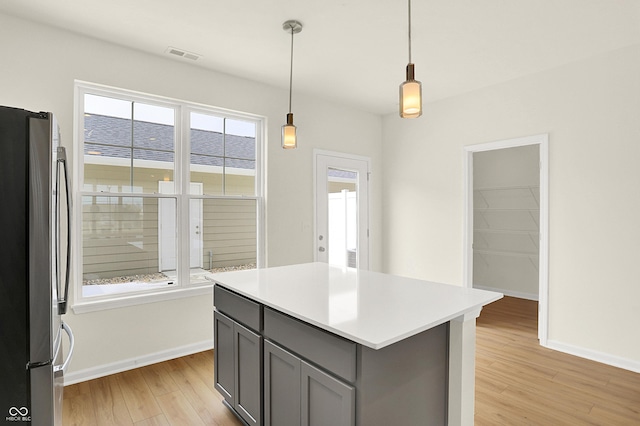 kitchen featuring light wood-style flooring, visible vents, light countertops, gray cabinets, and freestanding refrigerator