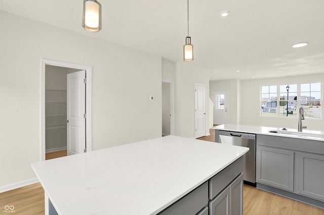 kitchen featuring a sink, a kitchen island, gray cabinets, and stainless steel dishwasher