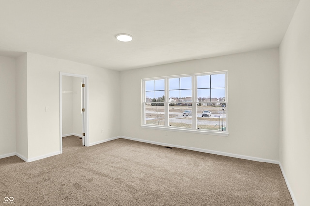 carpeted spare room featuring baseboards and visible vents