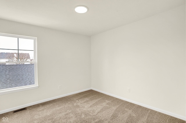 carpeted spare room with visible vents and baseboards