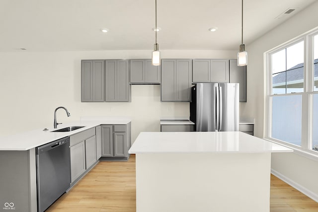 kitchen featuring appliances with stainless steel finishes, light wood-type flooring, gray cabinets, and a sink