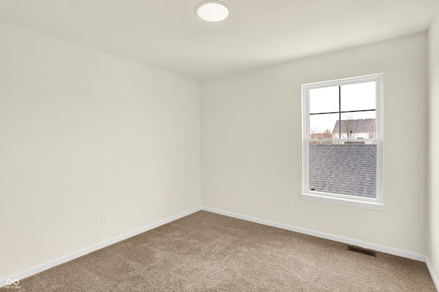 empty room with carpet, visible vents, and baseboards