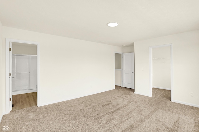 unfurnished bedroom with a closet, carpet, a walk in closet, and baseboards