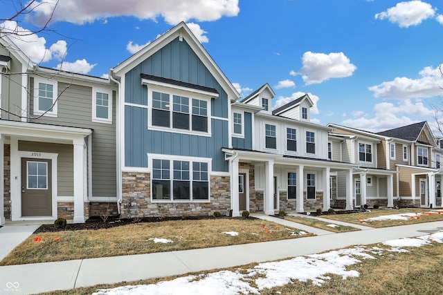 townhome / multi-family property with board and batten siding, stone siding, and a porch