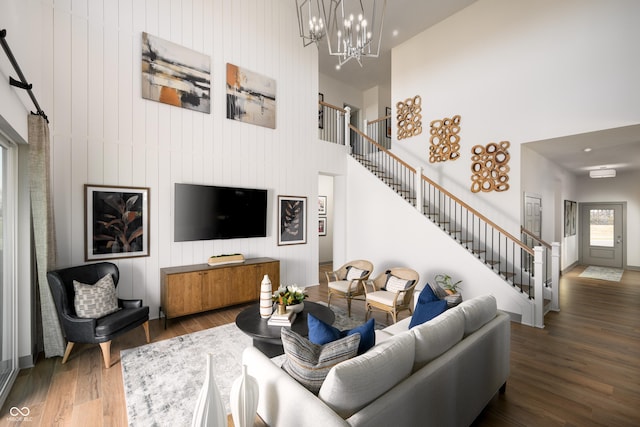 living area with an inviting chandelier, wood finished floors, a high ceiling, and stairs