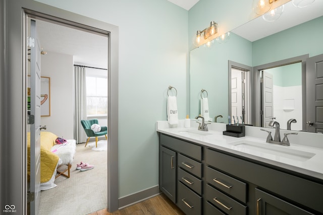 bathroom with double vanity, baseboards, a sink, and wood finished floors