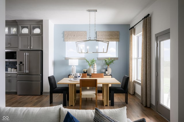 dining space with a wealth of natural light, baseboards, a chandelier, and wood finished floors