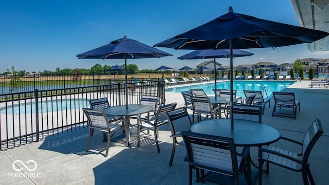 view of patio with a community pool, fence, and outdoor dining space