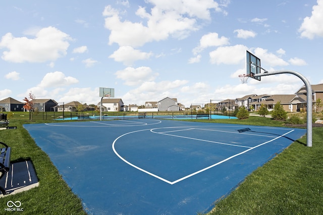 view of sport court with a lawn, a tennis court, community basketball court, fence, and a residential view