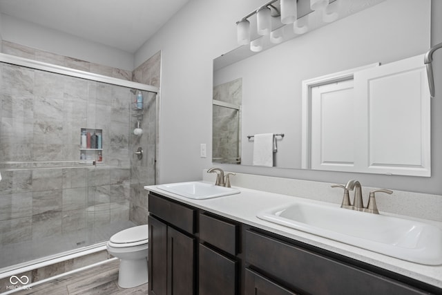 bathroom featuring wood finished floors, a sink, toilet, and a shower stall