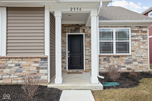 property entrance with stone siding and roof with shingles