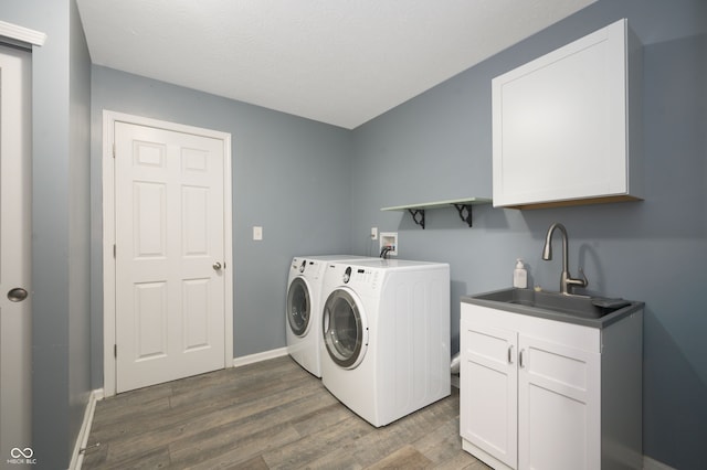 laundry area with wood finished floors, a sink, baseboards, washer and dryer, and cabinet space