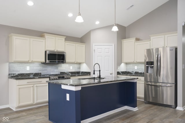 kitchen featuring visible vents, dark stone counters, lofted ceiling, appliances with stainless steel finishes, and a sink