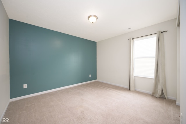 spare room with baseboards and light colored carpet