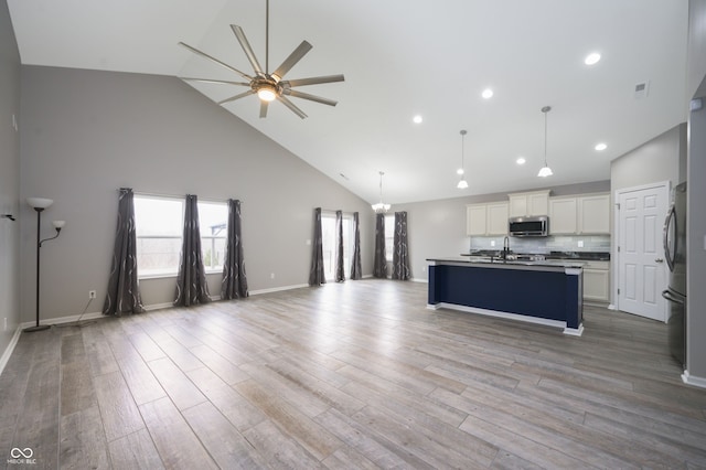 kitchen featuring wood finished floors, a sink, white cabinetry, open floor plan, and appliances with stainless steel finishes