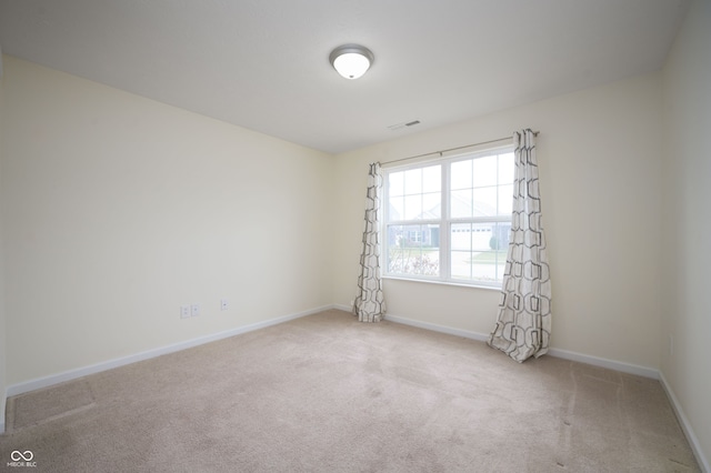 carpeted spare room with visible vents and baseboards