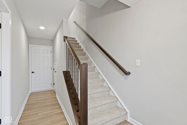 staircase featuring wood finished floors and baseboards