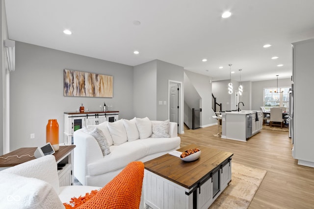 living room featuring baseboards, light wood-type flooring, an inviting chandelier, and recessed lighting