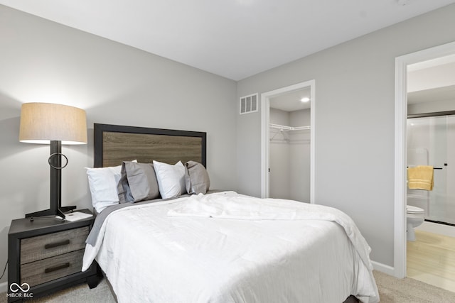 bedroom featuring baseboards, visible vents, connected bathroom, light colored carpet, and a closet