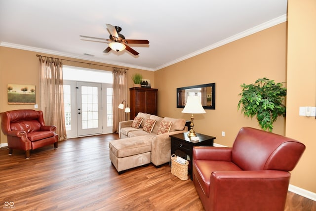 living room featuring crown molding, wood finished floors, baseboards, and ceiling fan