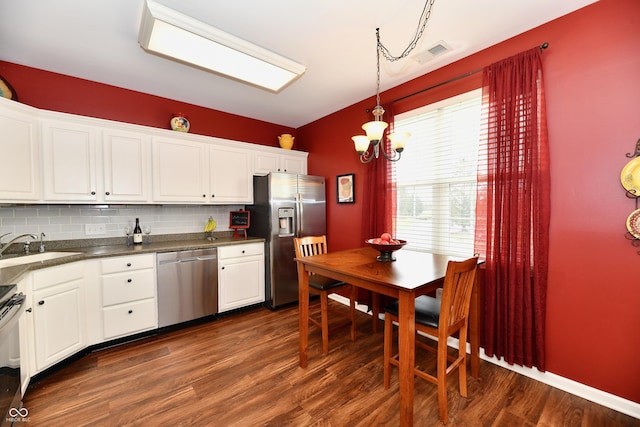 kitchen with visible vents, a sink, dark countertops, stainless steel appliances, and decorative backsplash