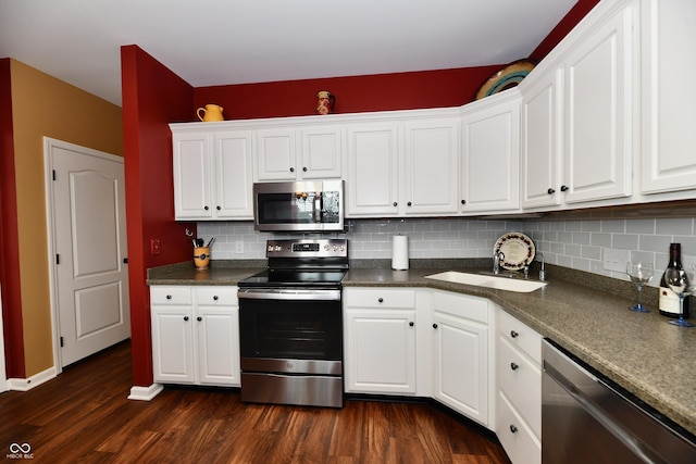 kitchen with tasteful backsplash, dark countertops, dark wood finished floors, white cabinetry, and stainless steel appliances