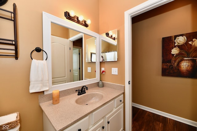 bathroom with baseboards, wood finished floors, and vanity