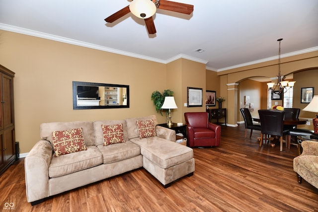 living area with arched walkways, wood finished floors, ornamental molding, and ceiling fan with notable chandelier