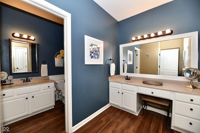 bathroom featuring toilet, vanity, baseboards, and wood finished floors