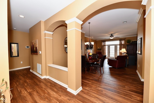 hall with visible vents, baseboards, dark wood finished floors, arched walkways, and ornate columns