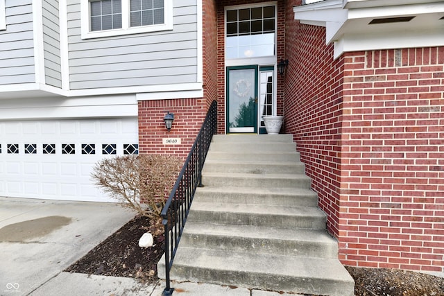 view of exterior entry with brick siding, driveway, and a garage